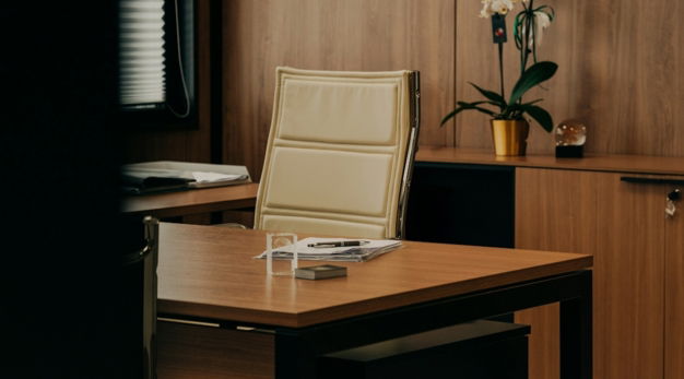 a desk with a chair and a vase of flowers